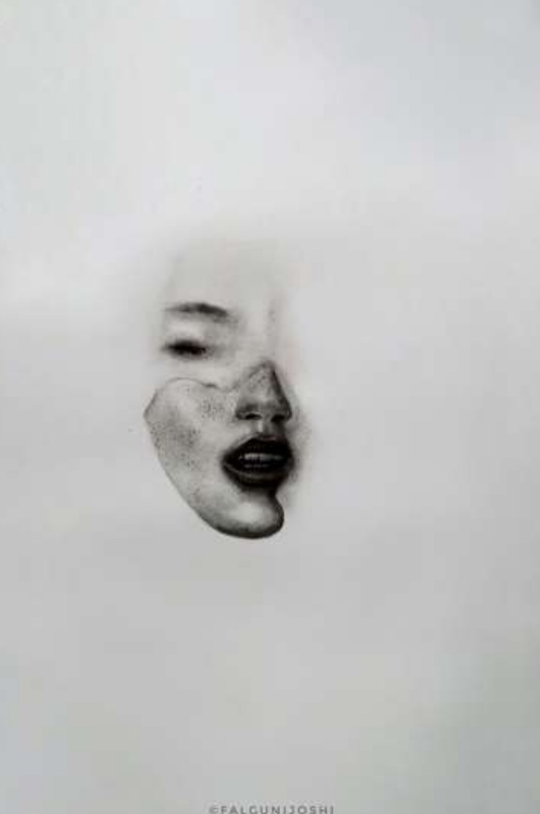 Fragmented charcoal face floating in white emptiness: one closed eye above a detached freckled nose, cheek, and parted dark lips.