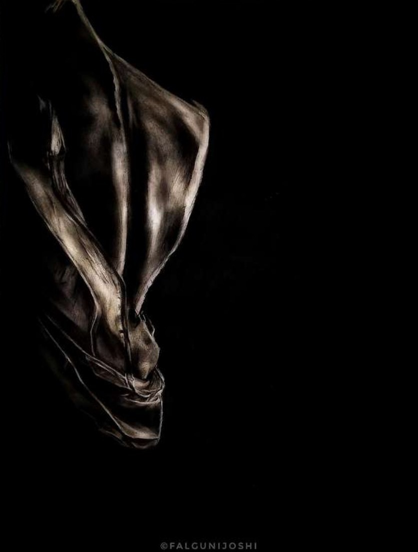 Golden-lit fabric twisting and draping downward out of a pure black background, its folds picked out in warm metallic highlights.
