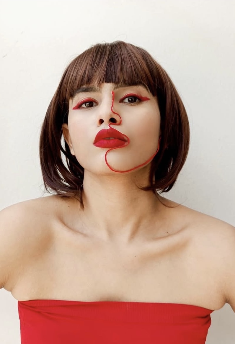 Self portrait: a red cotton thread traces down the artist's face, around her lips, and trails off below her jaw